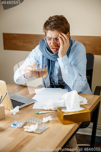 Image of Sick man while working in office, businessman caught cold, seasonal flu.