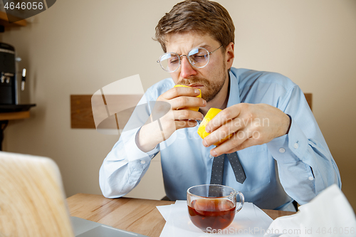 Image of Sick man while working in office, businessman caught cold, seasonal flu.