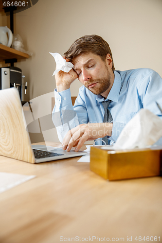 Image of Sick man while working in office, businessman caught cold, seasonal flu.