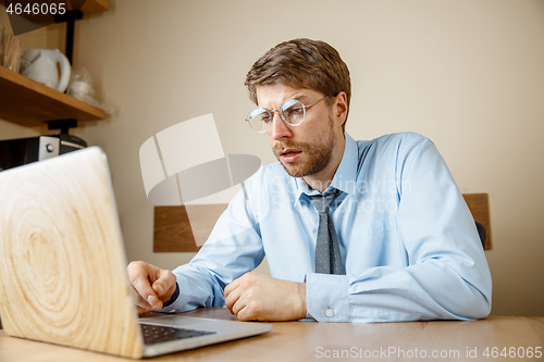 Image of Feeling sick and tired. Frustrated young man massaging his head while sitting at his working place in office