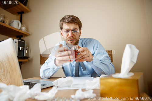 Image of Sick man while working in office, businessman caught cold, seasonal flu.