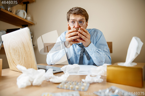 Image of Sick man while working in office, businessman caught cold, seasonal flu.