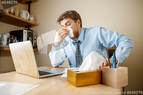 Image of Sick man while working in office, businessman caught cold, seasonal flu.