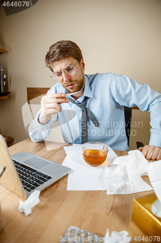 Image of Sick man while working in office, businessman caught cold, seasonal flu.