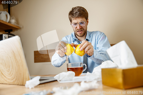 Image of Sick man while working in office, businessman caught cold, seasonal flu.