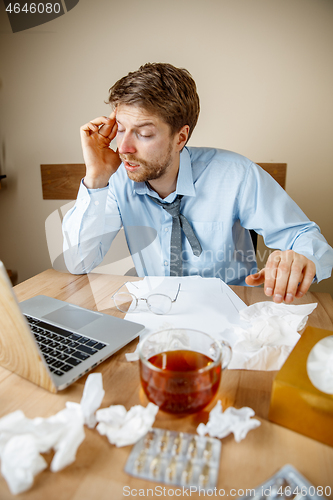 Image of Sick man while working in office, businessman caught cold, seasonal flu.