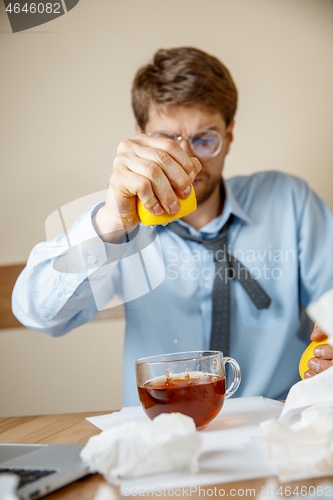 Image of Sick man while working in office, businessman caught cold, seasonal flu.