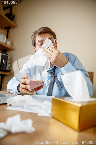 Image of Sick man while working in office, businessman caught cold, seasonal flu.