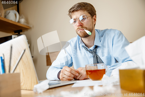 Image of Sick man while working in office, businessman caught cold, seasonal flu.