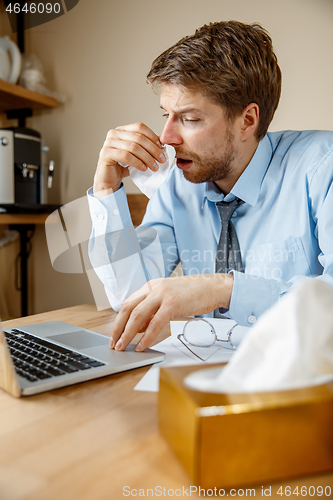 Image of Sick man while working in office, businessman caught cold, seasonal flu.