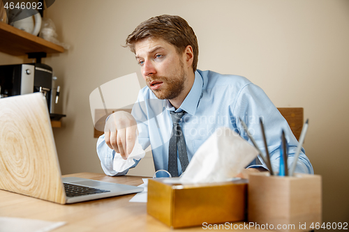 Image of Sick man while working in office, businessman caught cold, seasonal flu.