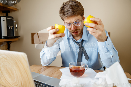 Image of Sick man while working in office, businessman caught cold, seasonal flu.