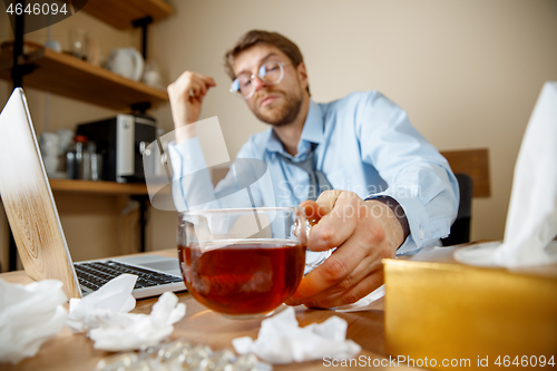 Image of Sick man while working in office, businessman caught cold, seasonal flu.