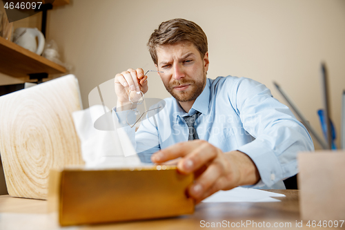 Image of Sick man while working in office, businessman caught cold, seasonal flu.