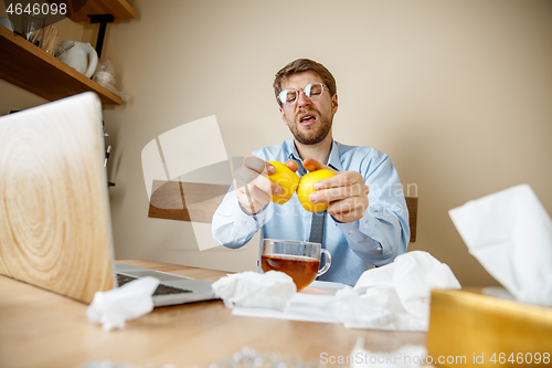 Image of Sick man while working in office, businessman caught cold, seasonal flu.