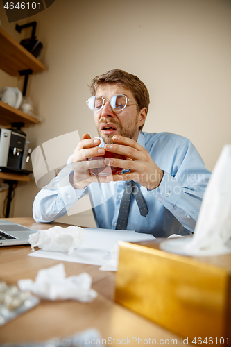 Image of Sick man while working in office, businessman caught cold, seasonal flu.