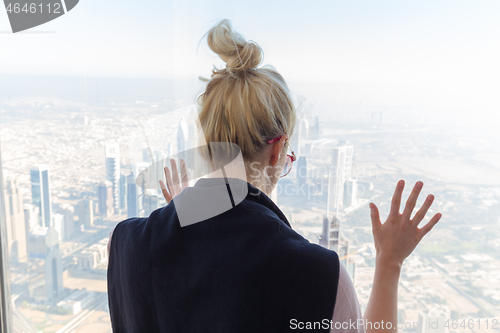 Image of Beautiful girl admiring the city view from observing platform at the top of the tallest skyscraper in the world, Burj Khalifa in Dubai, UAE.