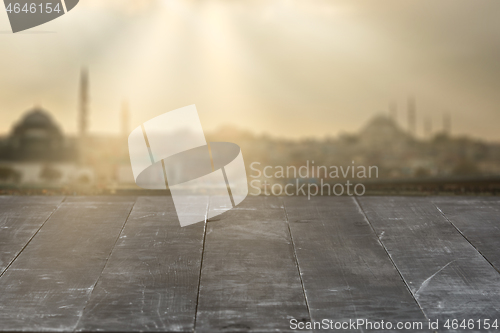 Image of Old wooden dark grey table for display your products on a blurred cityscape background.