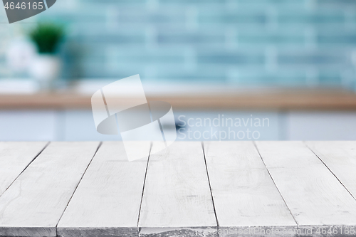 Image of Empty white wooden boards or table top over blurred kitchen interior on background. Template, mockup for display or montage. Close up, copy space