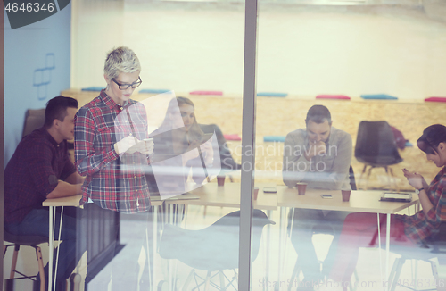 Image of business woman at office speaking by phone  team on meeting in b