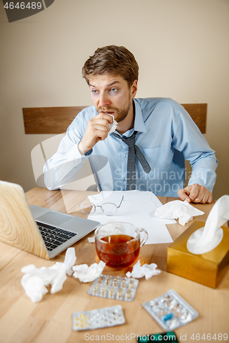 Image of Sick man while working in office, businessman caught cold, seasonal flu.