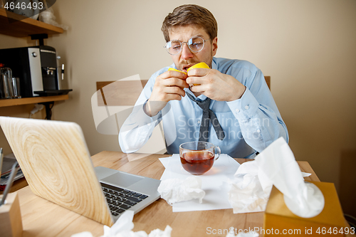 Image of Sick man while working in office, businessman caught cold, seasonal flu.