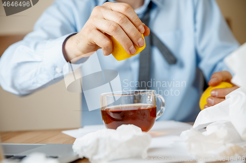 Image of Sick man while working in office, businessman caught cold, seasonal flu.