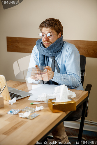 Image of Sick man while working in office, businessman caught cold, seasonal flu.