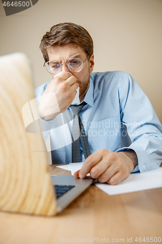 Image of Sick man while working in office, businessman caught cold, seasonal flu.