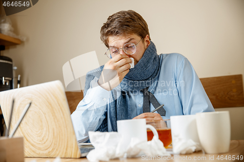 Image of Sick man while working in office, businessman caught cold, seasonal flu.