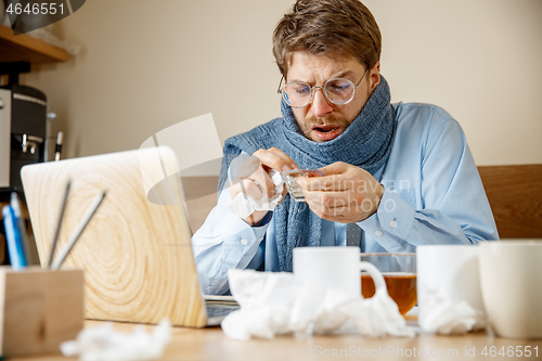 Image of Sick man while working in office, businessman caught cold, seasonal flu.