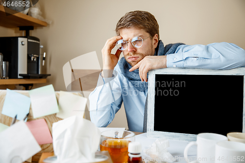 Image of Sick man while working in office, businessman caught cold, seasonal flu.