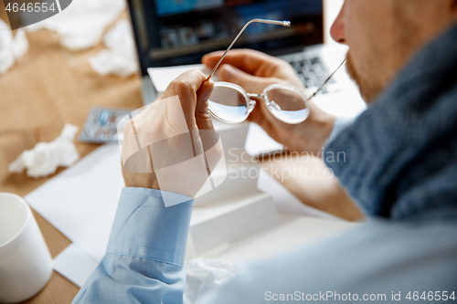 Image of Sick man while working in office, businessman caught cold, seasonal flu.