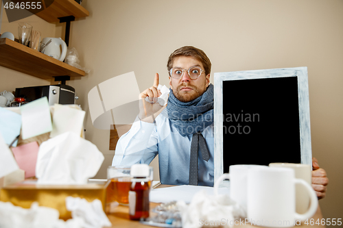 Image of Sick man while working in office, businessman caught cold, seasonal flu.