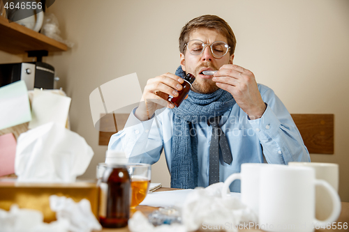 Image of Sick man while working in office, businessman caught cold, seasonal flu.