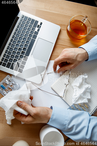 Image of Sick man while working in office, businessman caught cold, seasonal flu.