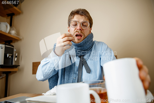 Image of Sick man while working in office, businessman caught cold, seasonal flu.