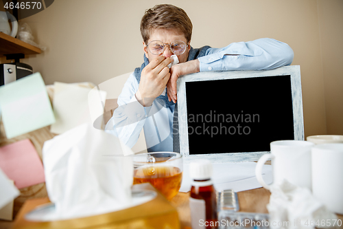 Image of Sick man while working in office, businessman caught cold, seasonal flu.