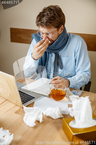 Image of Sick man while working in office, businessman caught cold, seasonal flu.