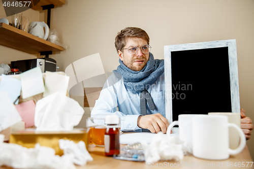 Image of Sick man while working in office, businessman caught cold, seasonal flu.