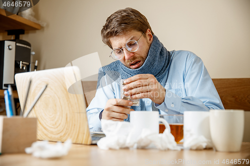 Image of Sick man while working in office, businessman caught cold, seasonal flu.