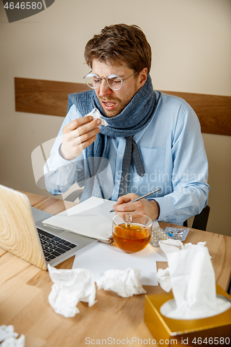 Image of Sick man while working in office, businessman caught cold, seasonal flu.