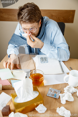 Image of Sick man while working in office, businessman caught cold, seasonal flu.