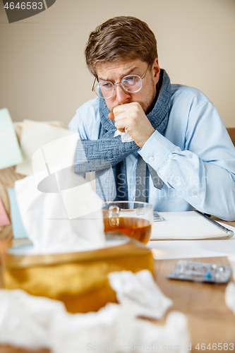 Image of Sick man while working in office, businessman caught cold, seasonal flu.