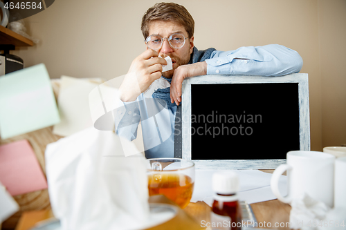 Image of Sick man while working in office, businessman caught cold, seasonal flu.