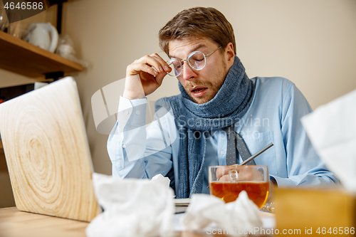 Image of Sick man while working in office, businessman caught cold, seasonal flu.