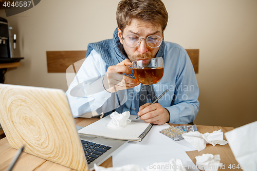 Image of Sick man while working in office, businessman caught cold, seasonal flu.