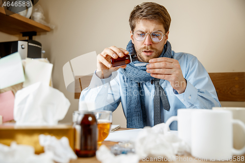 Image of Sick man while working in office, businessman caught cold, seasonal flu.