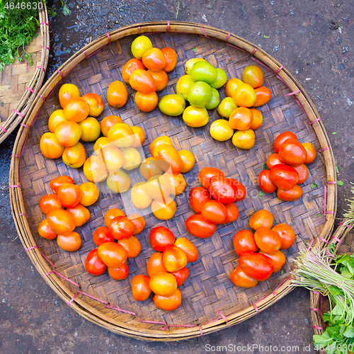 Image of Fresh red tomatoes in basket beeing sold on local asian farmers market.