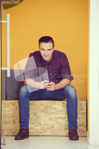 Image of man in crative box working on smart phone